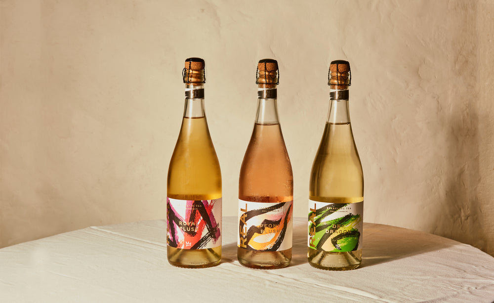 Three bottle's of REAL Naturally Fermented Sparkling Tea's stands elegantly on a table. The bottles promise a luxurious and sophisticated alcohol-free experience.